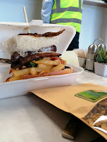 Steak strips piled on golden chips in a takeaway box
